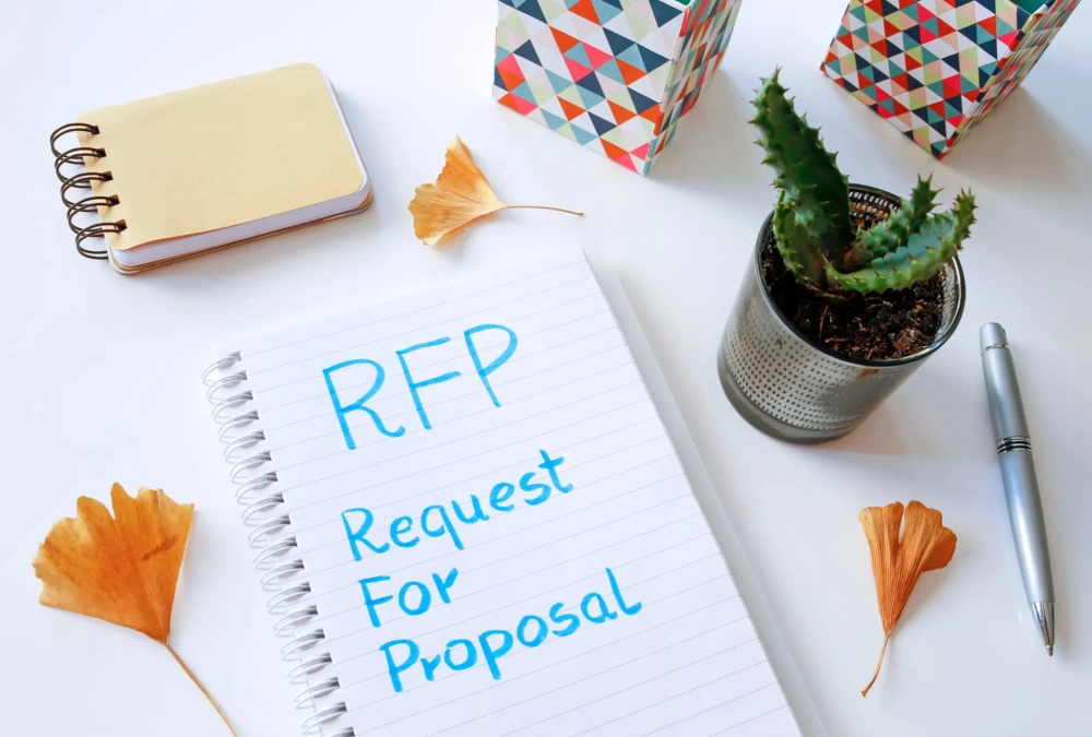 A notepad with 'RFP Request For Proposal' written on it, surrounded by office items.