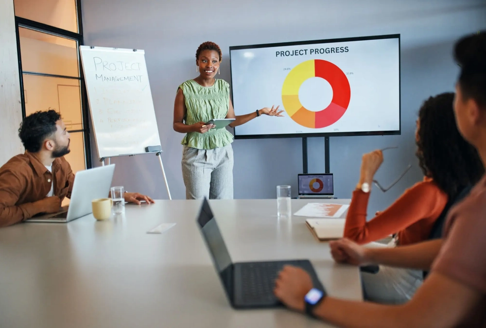 A woman presenting a project progress report to colleagues in a meeting room.